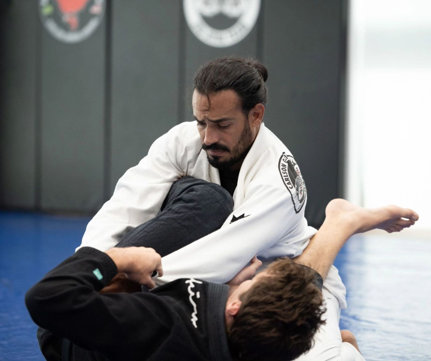 Adult students training guard passing in gi